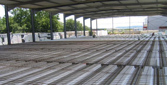 Ossature métallique de l'intérieur d'un bâtiment partiellement construit, avec dalles de béton et armatures.