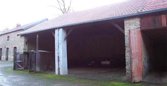 Grange ouverte avec murs en pierre patinée et toit en tuiles rouges.