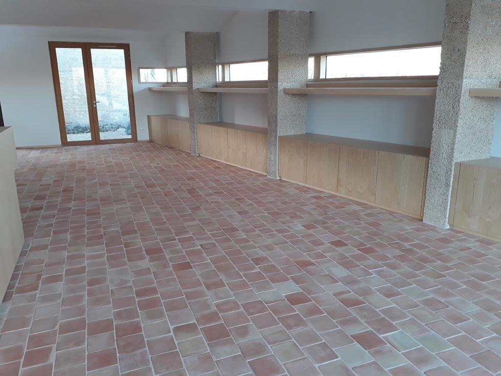 Pose de carreaux de terre cuite sur une grande surface dans une habitation