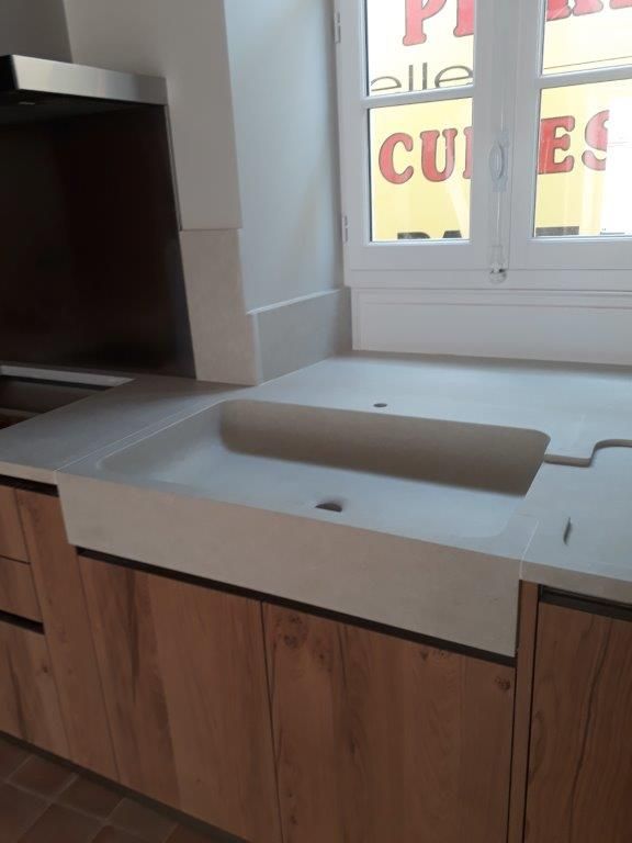 Plan de travail de cuisine avec évier intégré et placards en bois sous une fenêtre