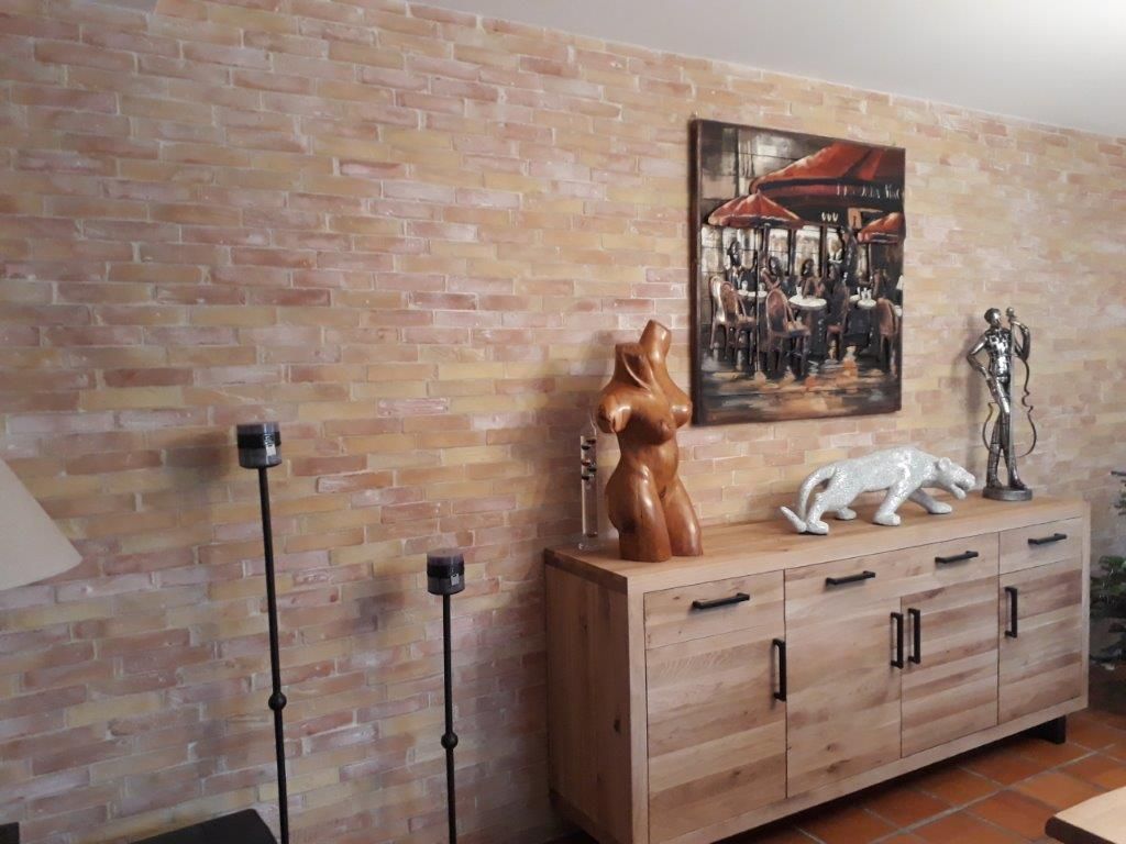 Buffet en bois orné de sculptures d'animaux et d'un tableau encadré, adossé à un mur de briques.