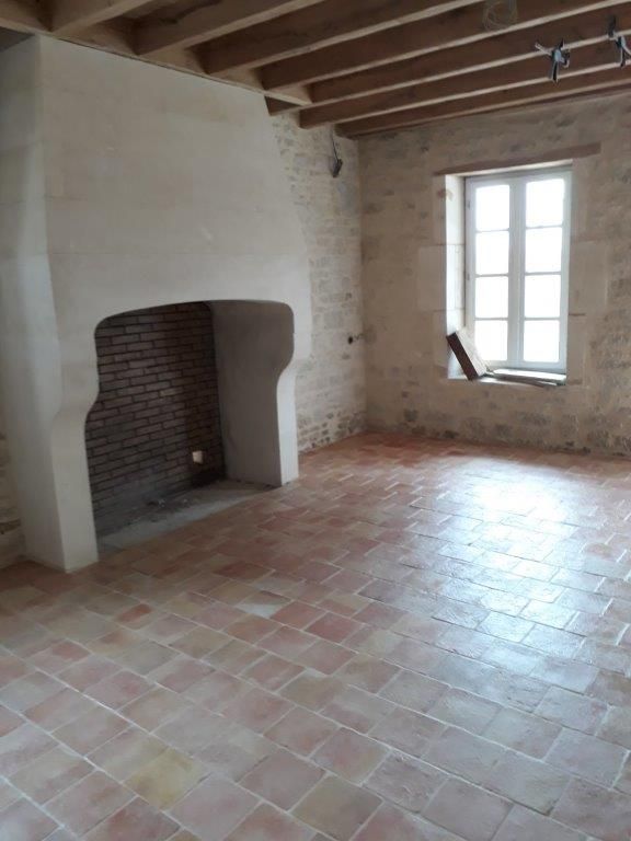 Pièce rustique vide avec murs en plâtre blanc, cheminée en briques, poutres apparentes et une fenêtre