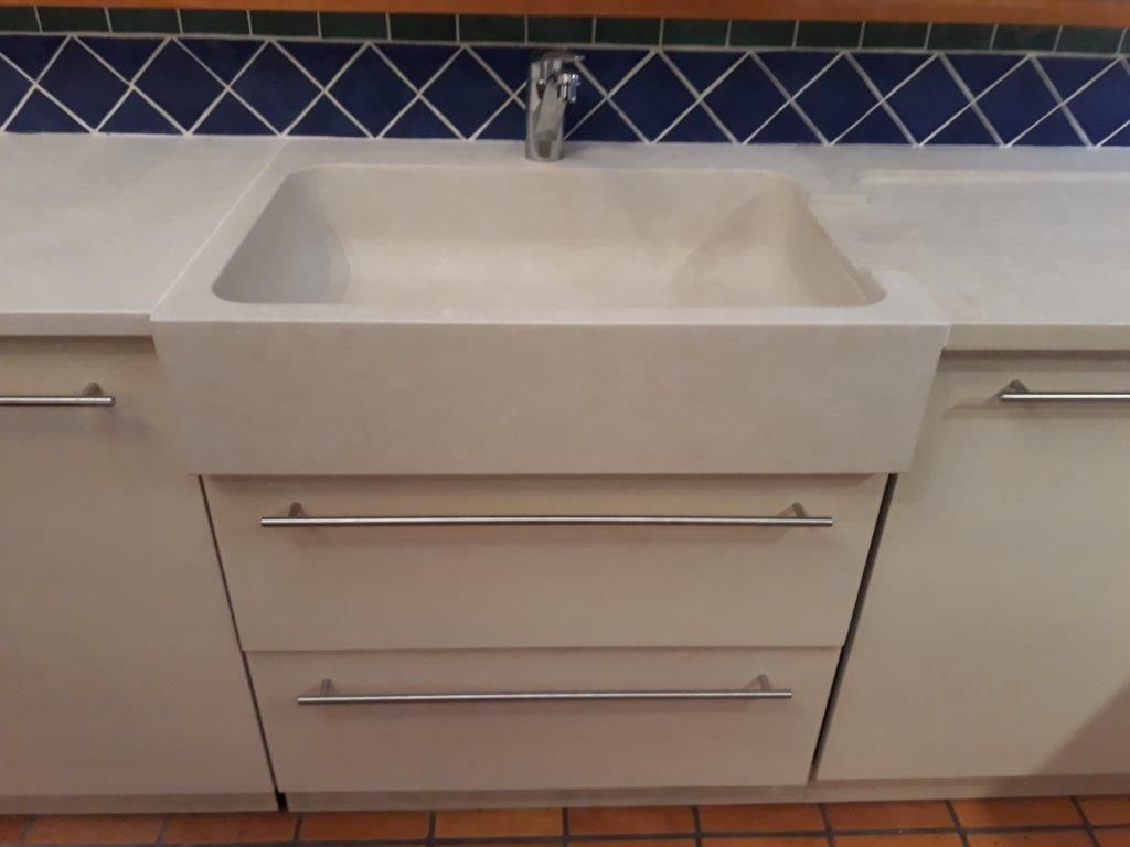 Meuble-lavabo blanc moderne avec vasque rectangulaire et poignées chromées, sur fond de crédence en carrelage bleu.