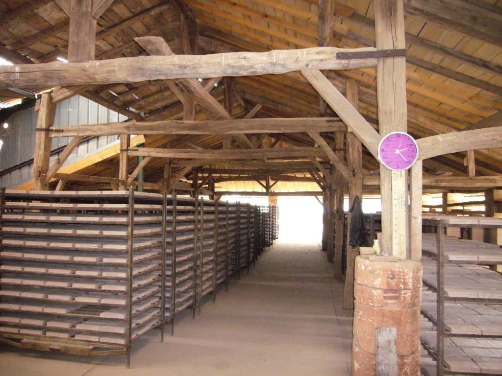 Intérieur rustique d'une grange avec poutres en bois et étagères superposées bordant une allée centrale.
