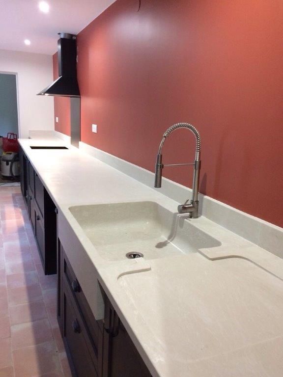 Évier pour cuisine moderne avec mur rouge, plan de travail blanc et meubles noir