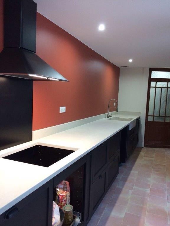 Cuisine moderne avec mur rouge, plan de travail blanc et meubles noir