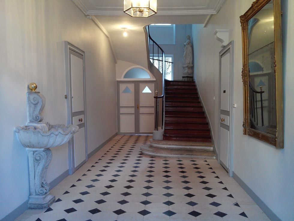 Pose de carreaux en octogone noir et blanc dans un hall d'entrée avec escalier