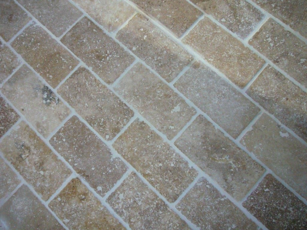 Motif diagonal de pavage en briques brun clair avec des lignes de mortier grises et une texture usée et mouchetée