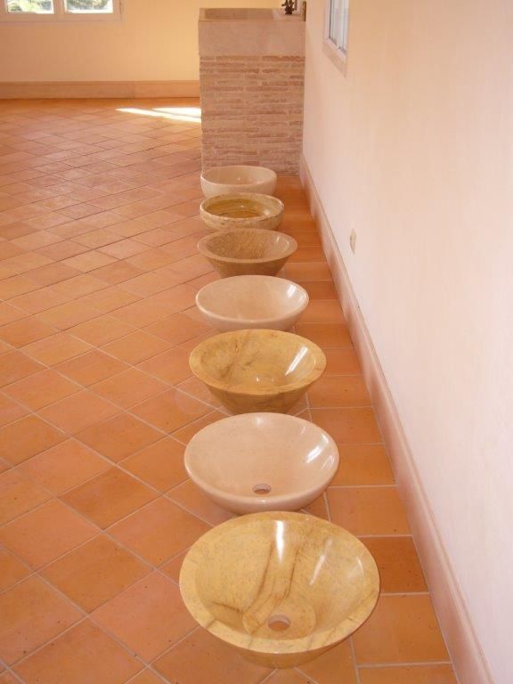 Une rangée de bols décoratifs est alignée le long d'un mur de couloir carrelé en terre cuite.