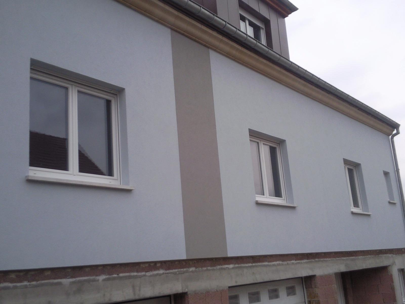 Extérieur d'un bâtiment bleu clair avec des fenêtres à cadre blanc, un garage et une bande d'accent marron.