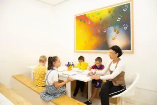 Una mujer está sentada en una mesa con un grupo de niños.