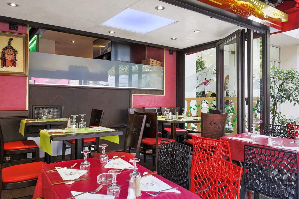 Intérieur de restaurant moderne avec tables rouges, chaises sombres et décoration murale colorée