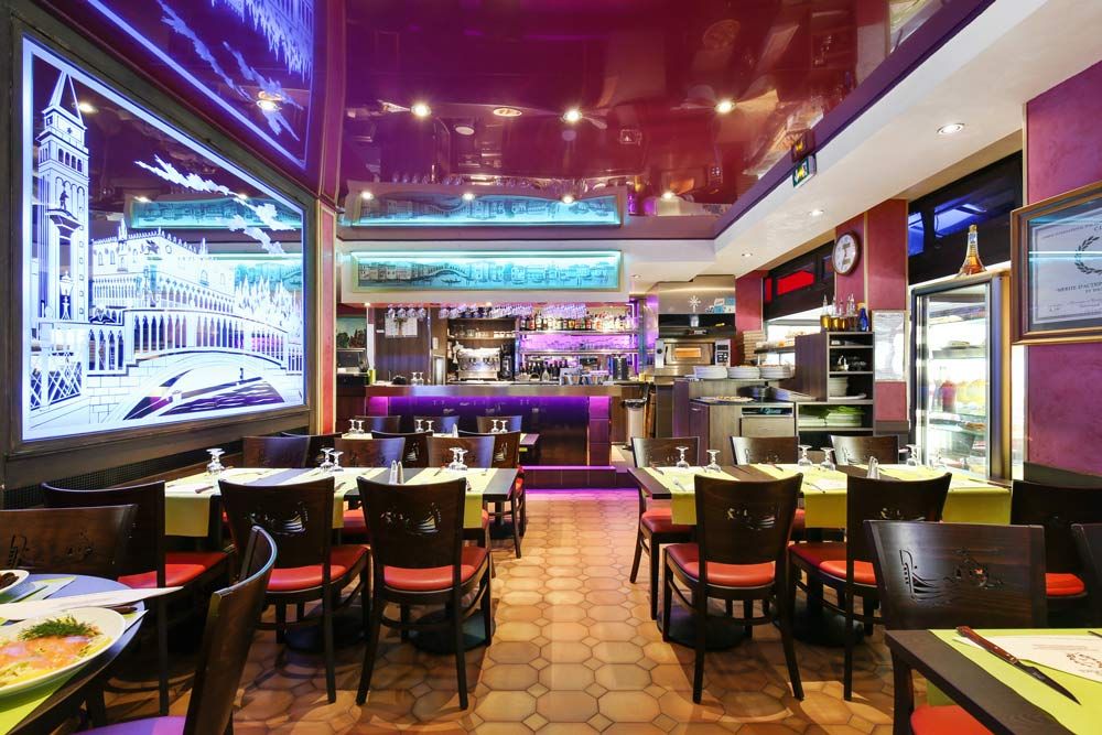 Restaurant moderne vide avec des lumières colorées, des tables, des chaises et un grand écran mural