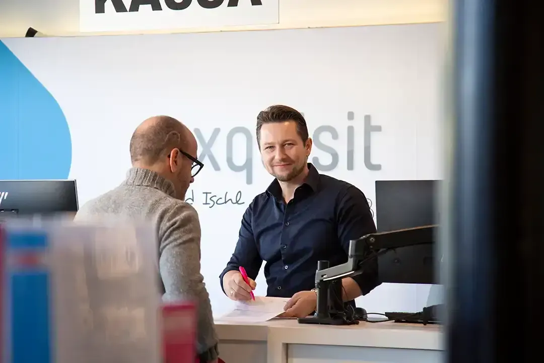 Zwei Männer sitzen an einer Ladentheke und unterhalten sich.