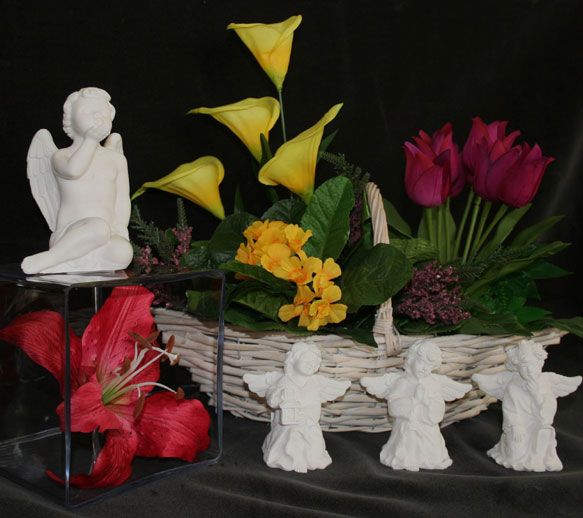 Figurines d'anges blancs et composition florale dans un panier : lys, tulipes et arums.