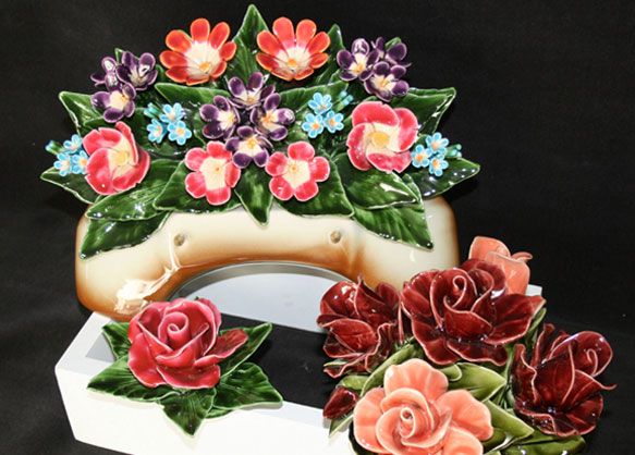 Composition florale en céramique avec des fleurs rouges, violettes et bleues, sur un fond beige.