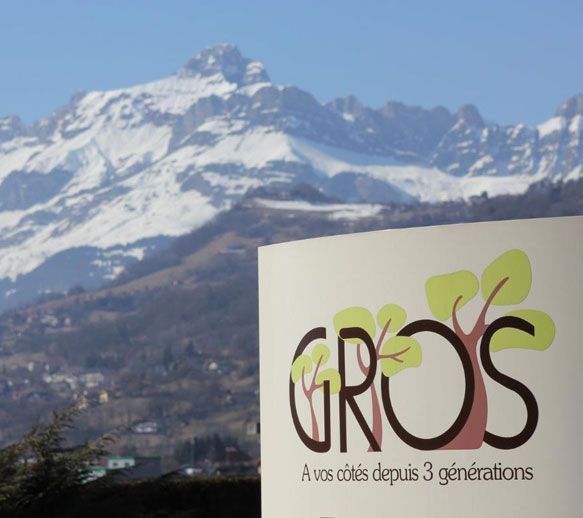 Logo des Pompes Funèbres Gros sur fond de montagnes.