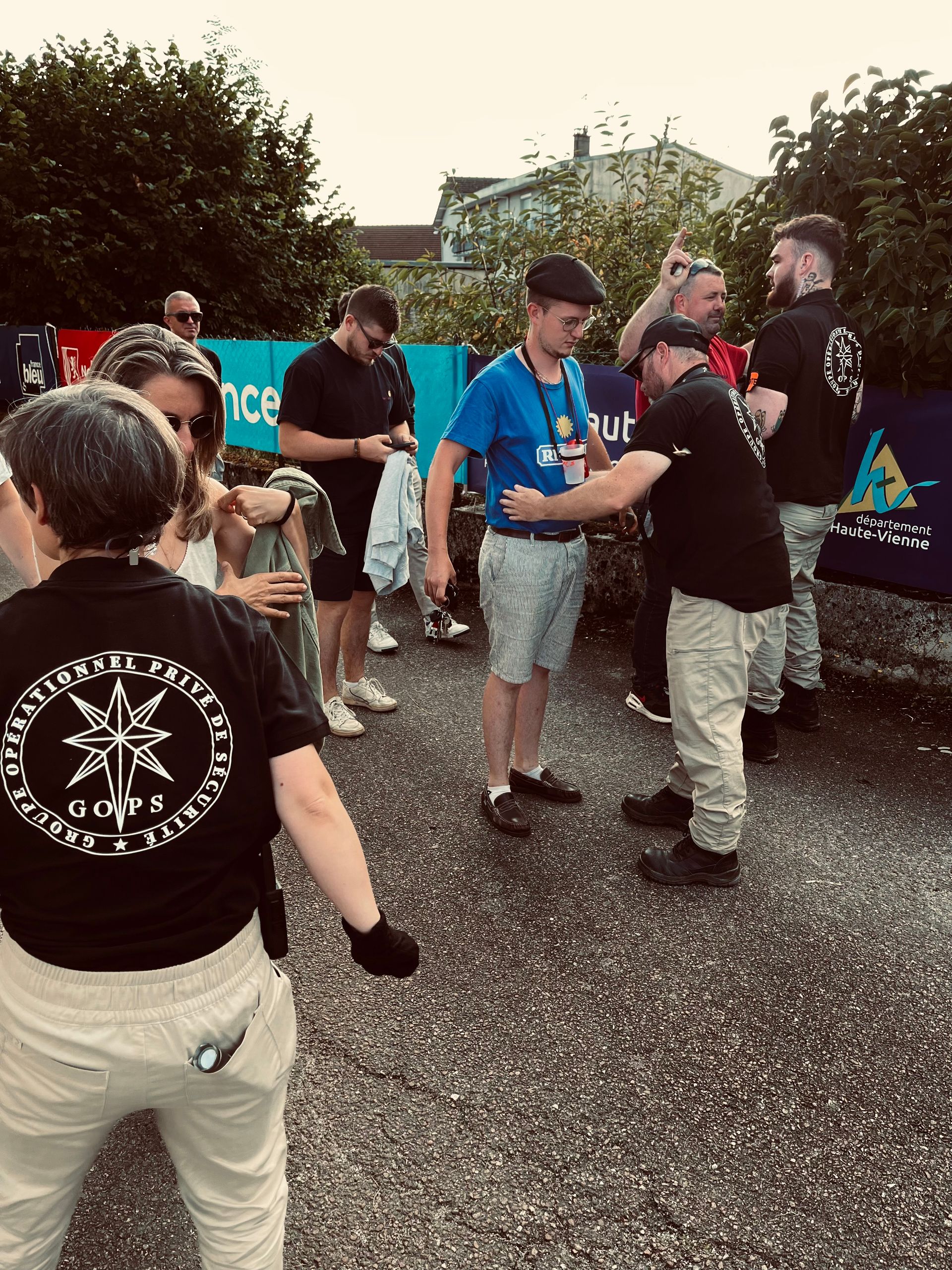Un groupe de personnes célèbre une cérémonie de remise de médailles en plein air. Un homme en chemise bleue reçoit une médaille d'un autre.