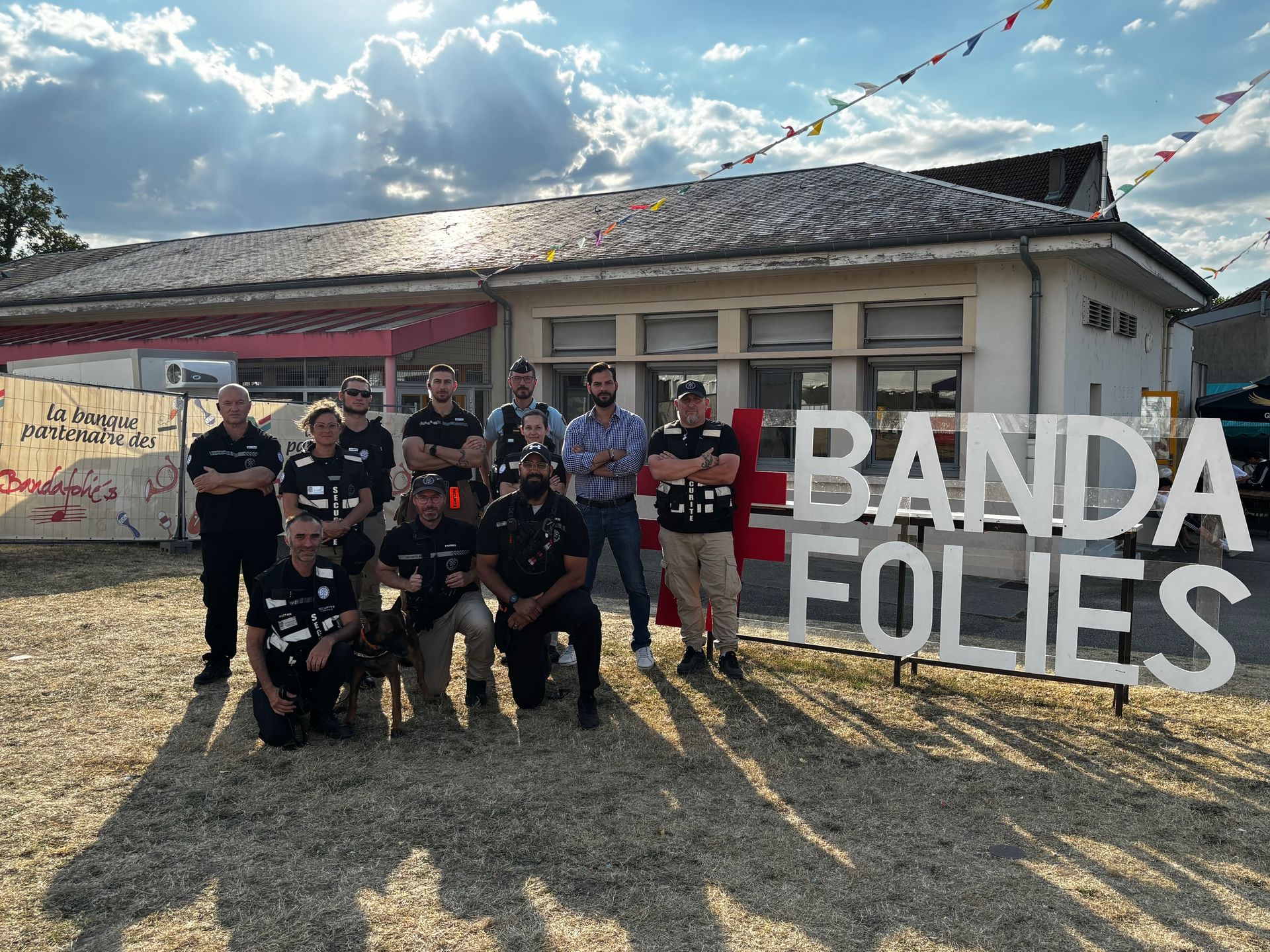 Groupe de personnes posant devant un immeuble, panneau