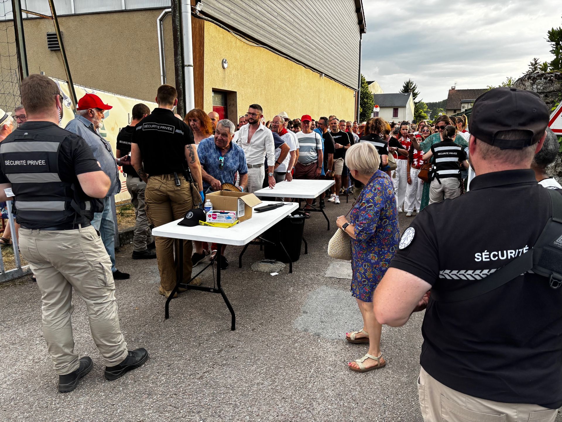 Rassemblement de personnes, éventuellement lors d'un événement, en présence du personnel de sécurité. En extérieur, en journée.