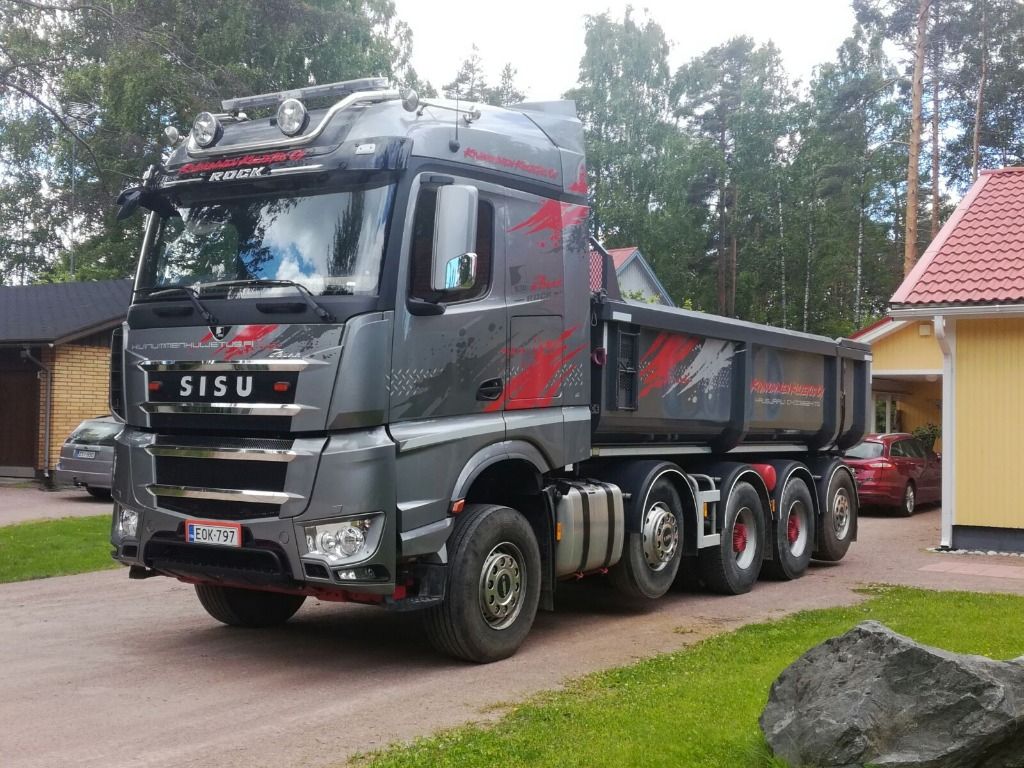 Harmaa ja punainen Sisu-kippiauto pysäköitynä asuinalueen pihatielle.