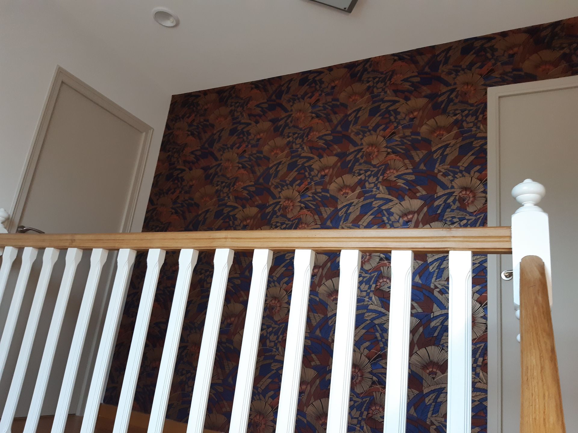 Papier peint floral en haut d'escalier et garde-corps en bois et de peinture blanche