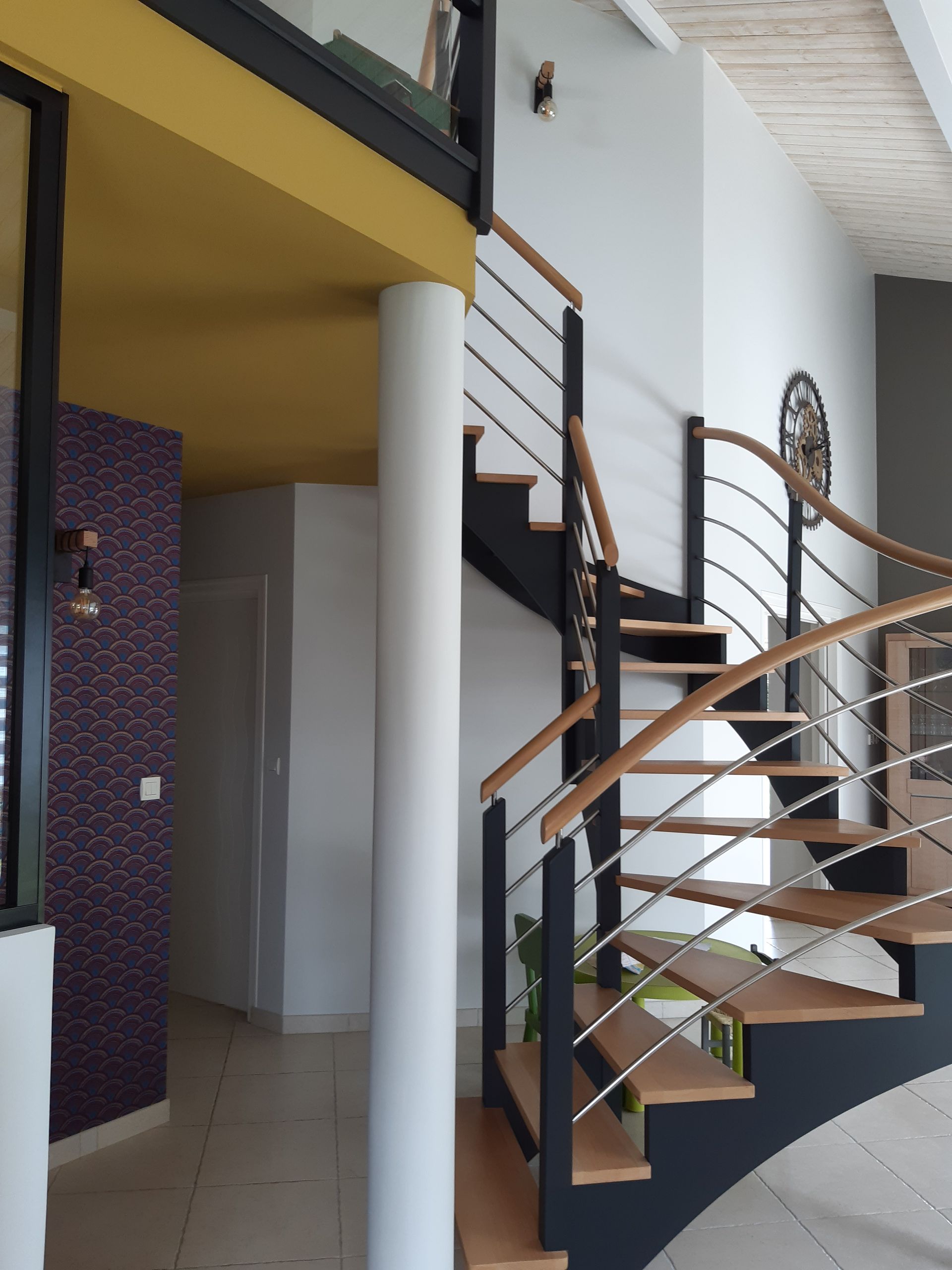 Escalier en fer noir et en bois entourant une colonne de support