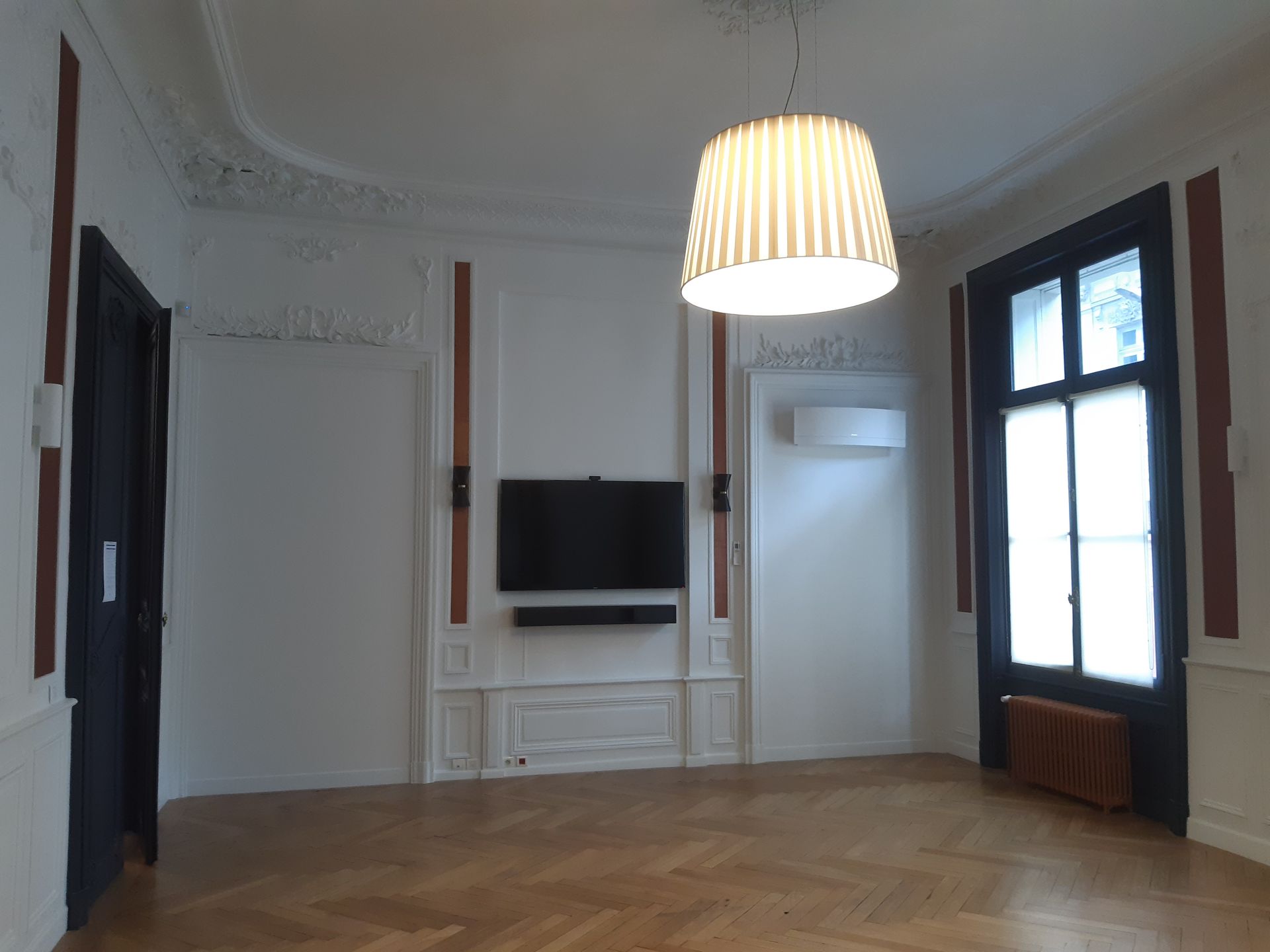 Salon vide et boiserie avec télévision intégrée au mur