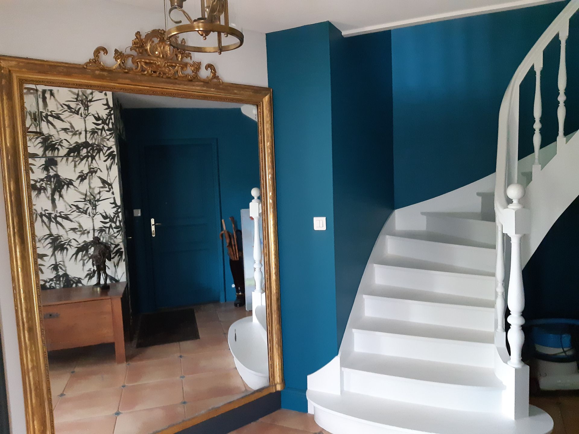 Escalier blanch avec murs bleus et grand miroir avec contour doré