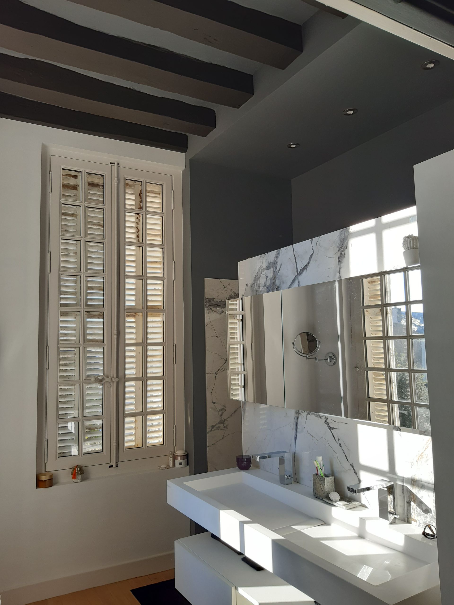 Photo de salle de bains avec miroir et fenêtre fermée avec des volets