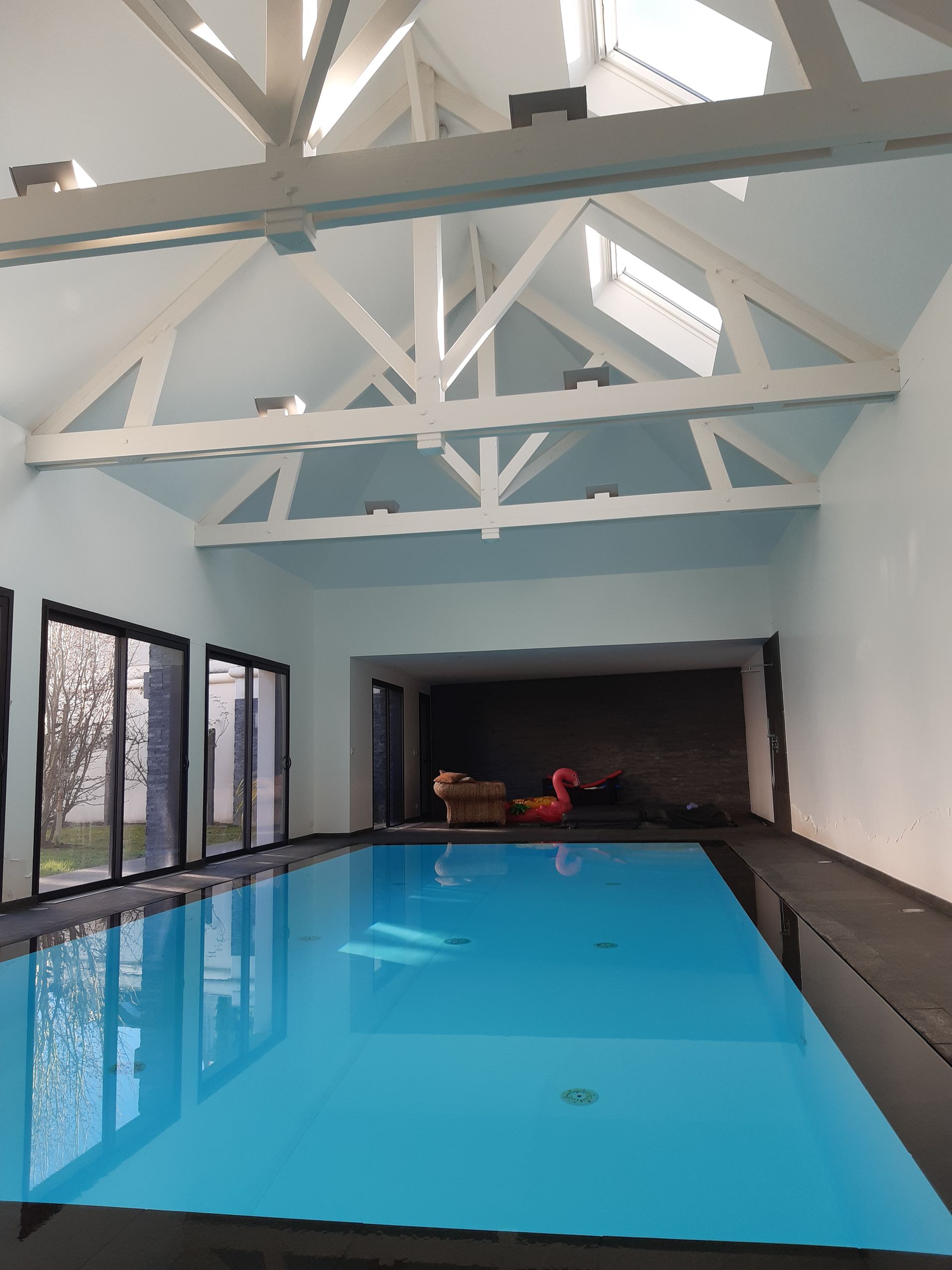 Piscine intérieure avec charpente peinte et apparente