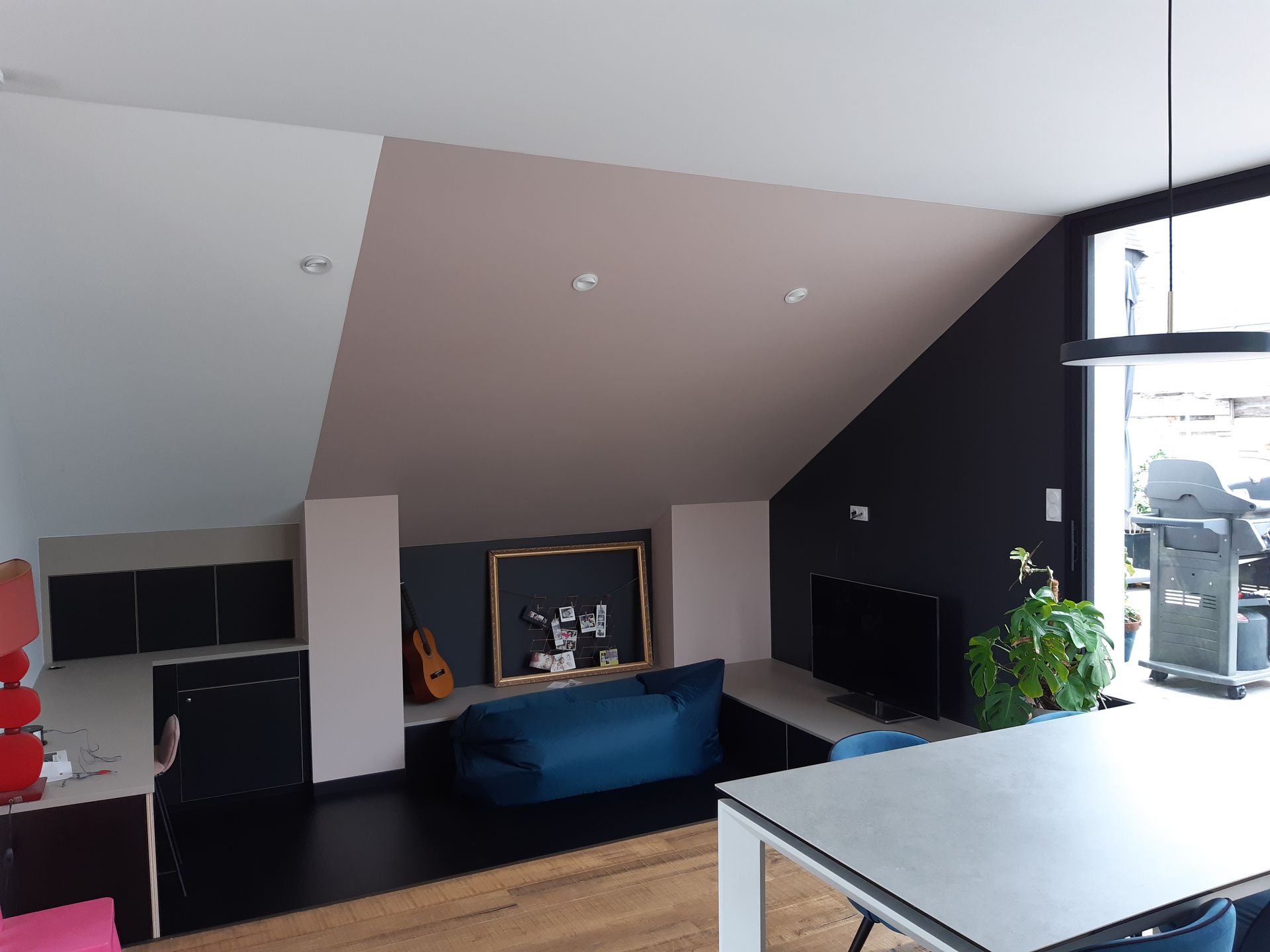 Salon avec canapé et télévision sous les combles aménagés