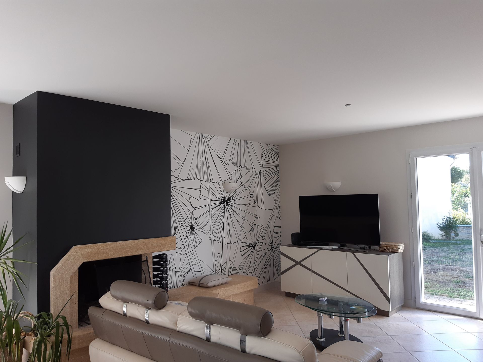 Salon avec canapé encastré dans le mur noir, meuble TV et télévision avec une partie du mur avec papier peint