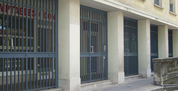 Entrée du bâtiment avec portails et colonnes de sécurité en métal gris.