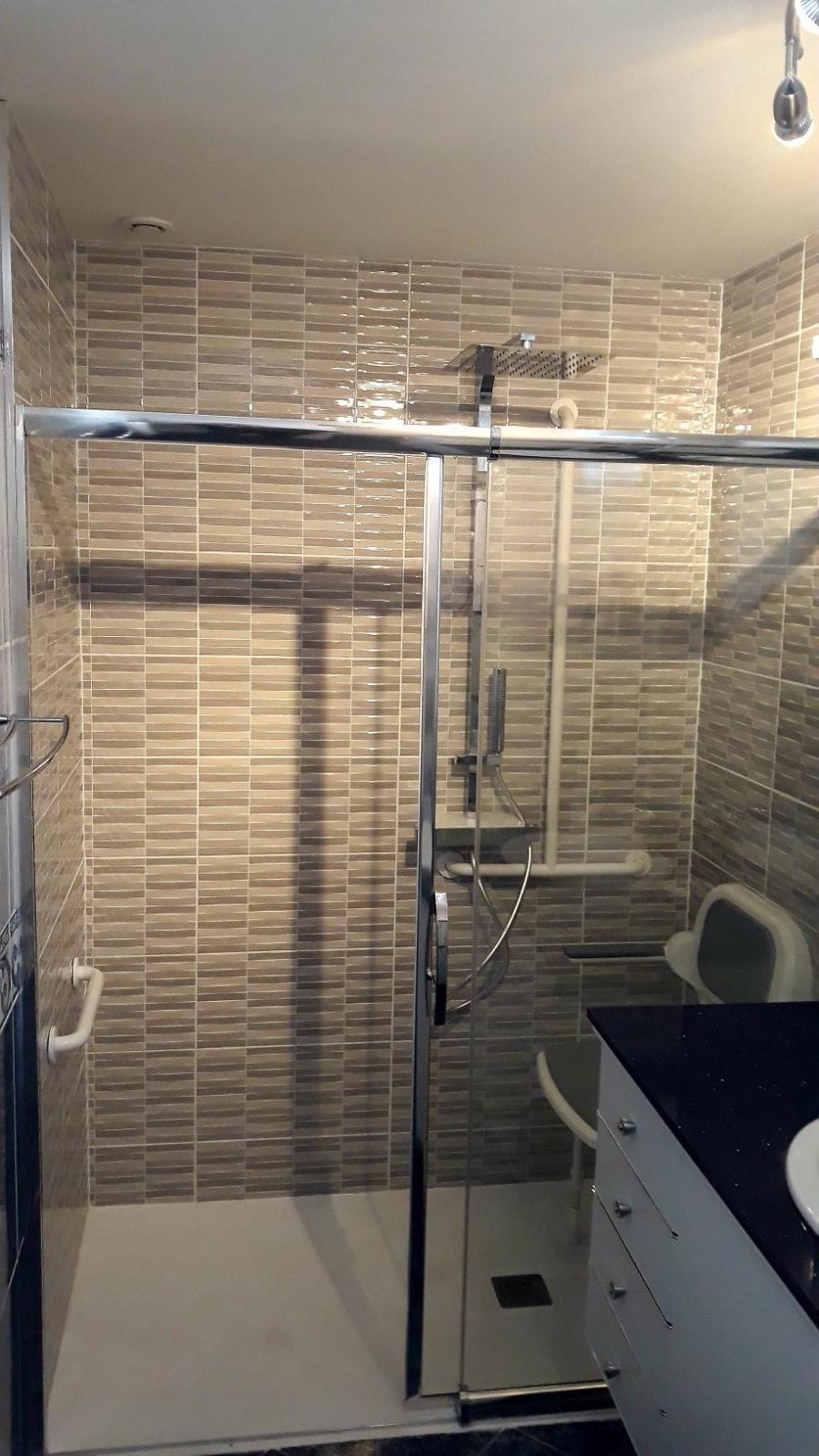 Douche PMR avec barres de maintien et siège.