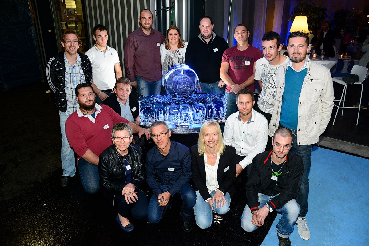 Un groupe de personnes pose à l'intérieur autour d'une sculpture de glace bleue lumineuse