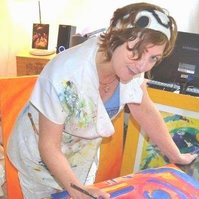 Femme peignant, portant un bandeau et un tablier. Œuvre abstraite colorée au premier plan. Pièce baignée de lumière.