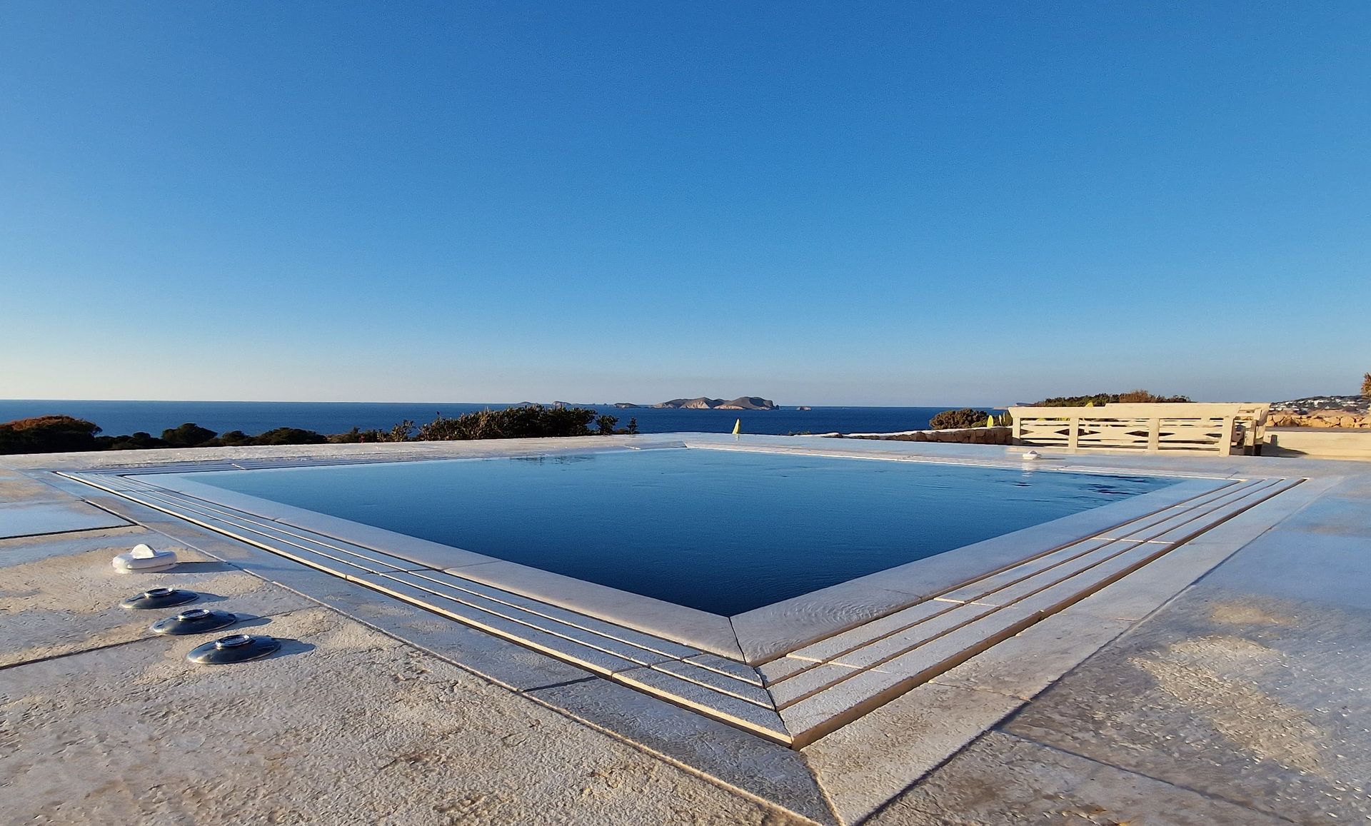 Piscina en la azotea con vista al mar en un día soleado.