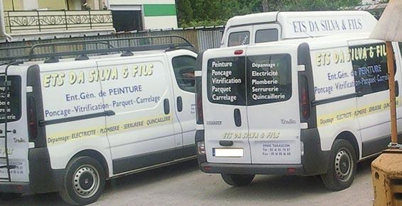 Des fourgonnettes blanches de transport de passagers avec des panneaux publicitaires sont stationnées dans une rue, vues de l'arrière et du côté.