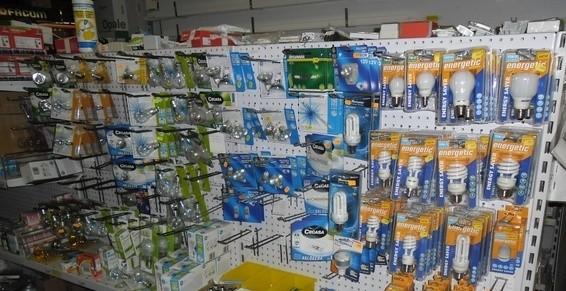 Rayon du magasin proposant des articles de quincaillerie et des appareils électriques dans des emballages bleus, verts et oranges.