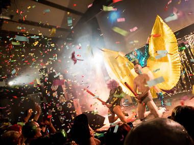 A group of people are dancing on a stage with confetti falling from the ceiling.