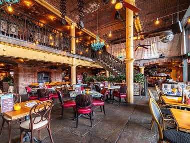 A restaurant filled with tables and chairs and a staircase.