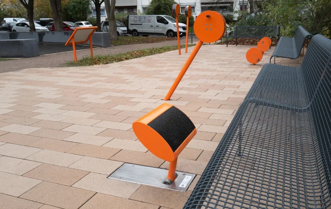 Oranssit ja mustat aurinkokennolla toimivat polkuvalot laatoitetulla kävelytiellä puiston penkin vieressä