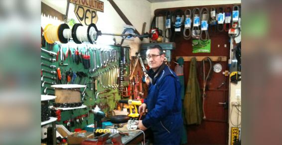 Employé de Jardi'Dép dans l'atelier devant ses outils de réparation.