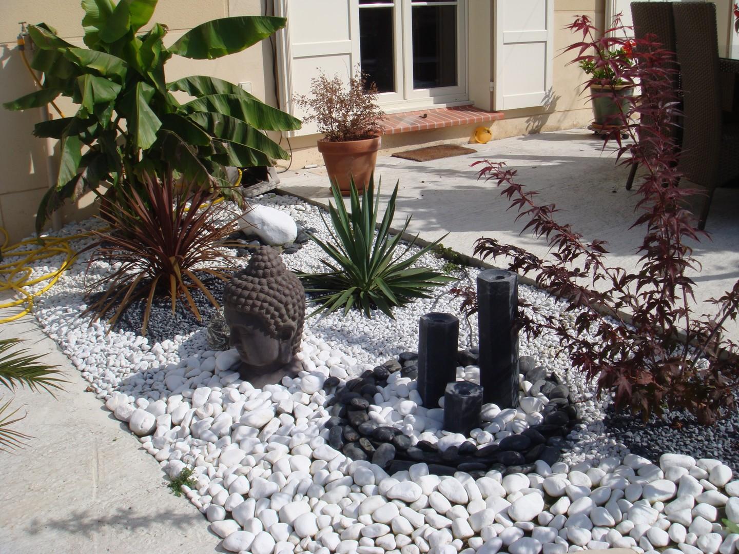 Massif avec graviers blancs, plantes et sculptures