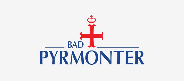 Logo von Bad Pyrmont, Deutschland: rotes Kreuz mit Krone über blauem Text auf weißem Hintergrund.