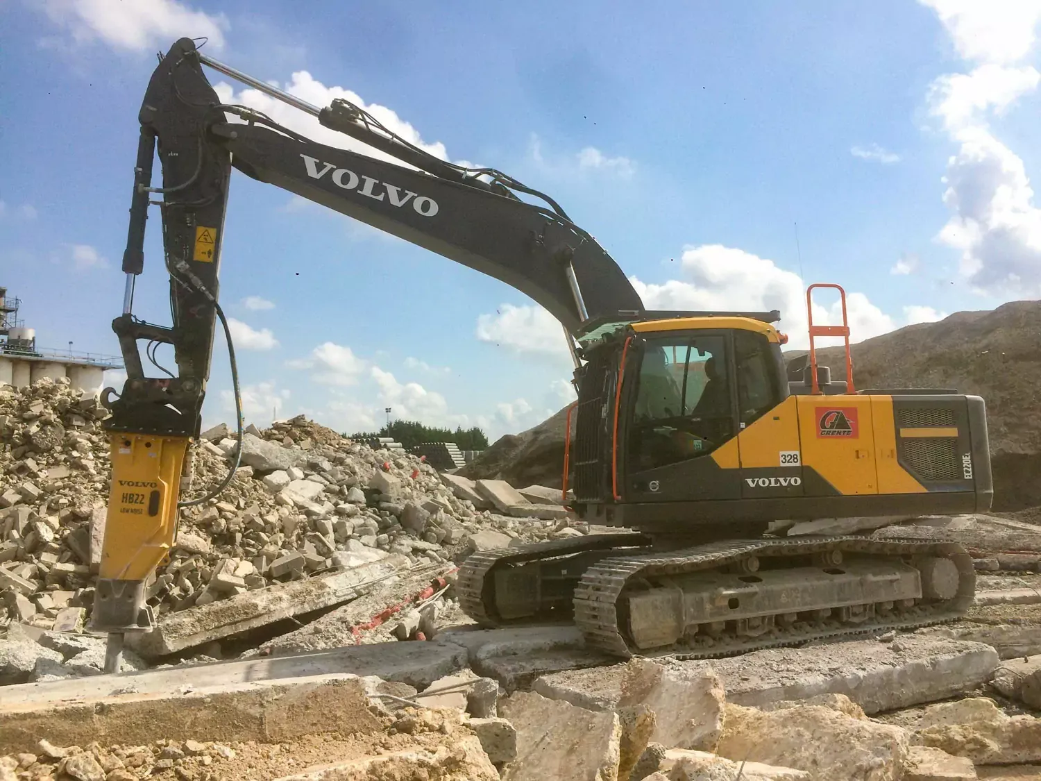 Une pelle Volvo équipée d'un marteau de démolition brise des blocs de béton.