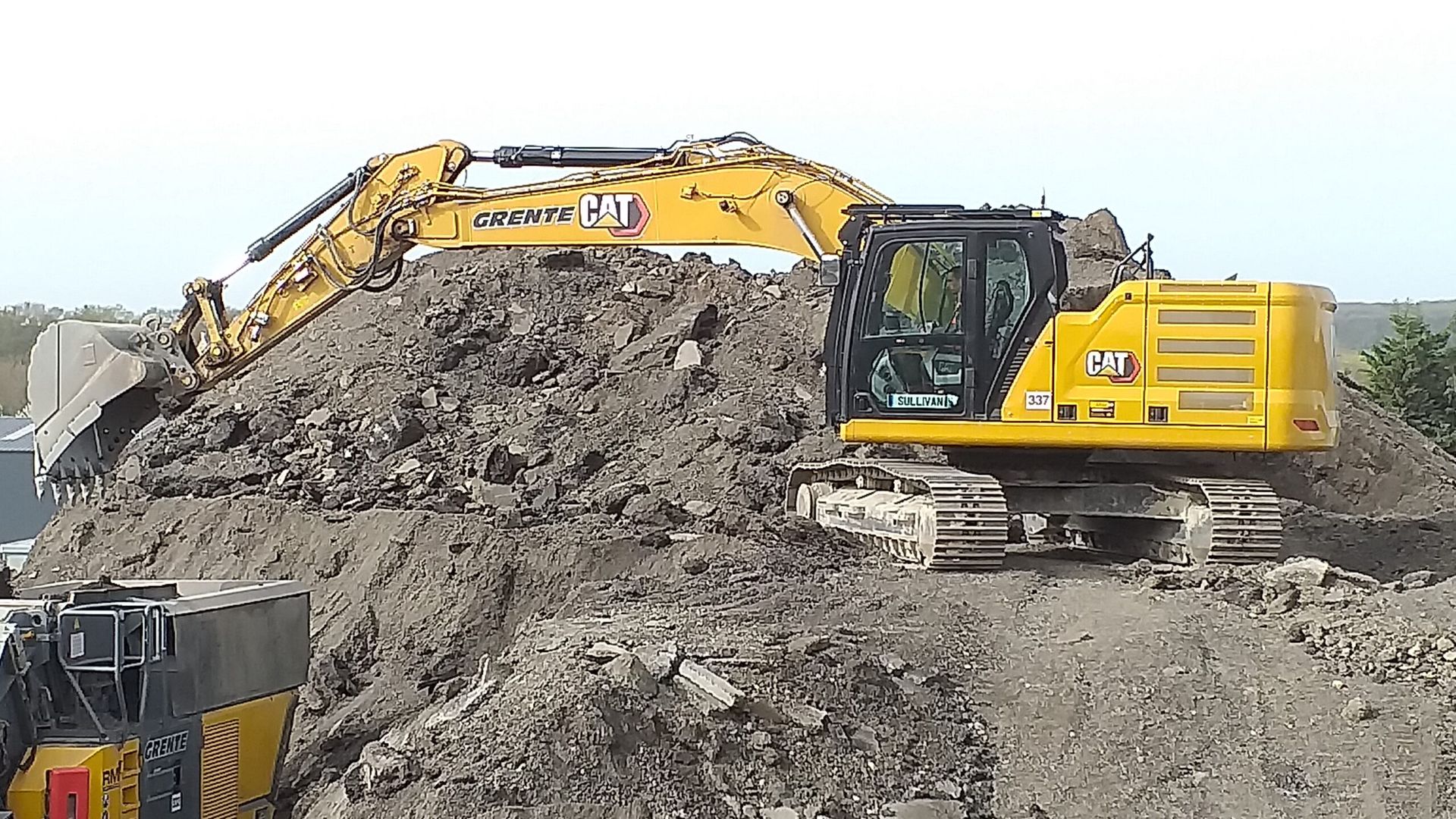 Pelle mécanique Caterpillar jaune sur un tas de terre, en train de creuser. Chantier de construction.