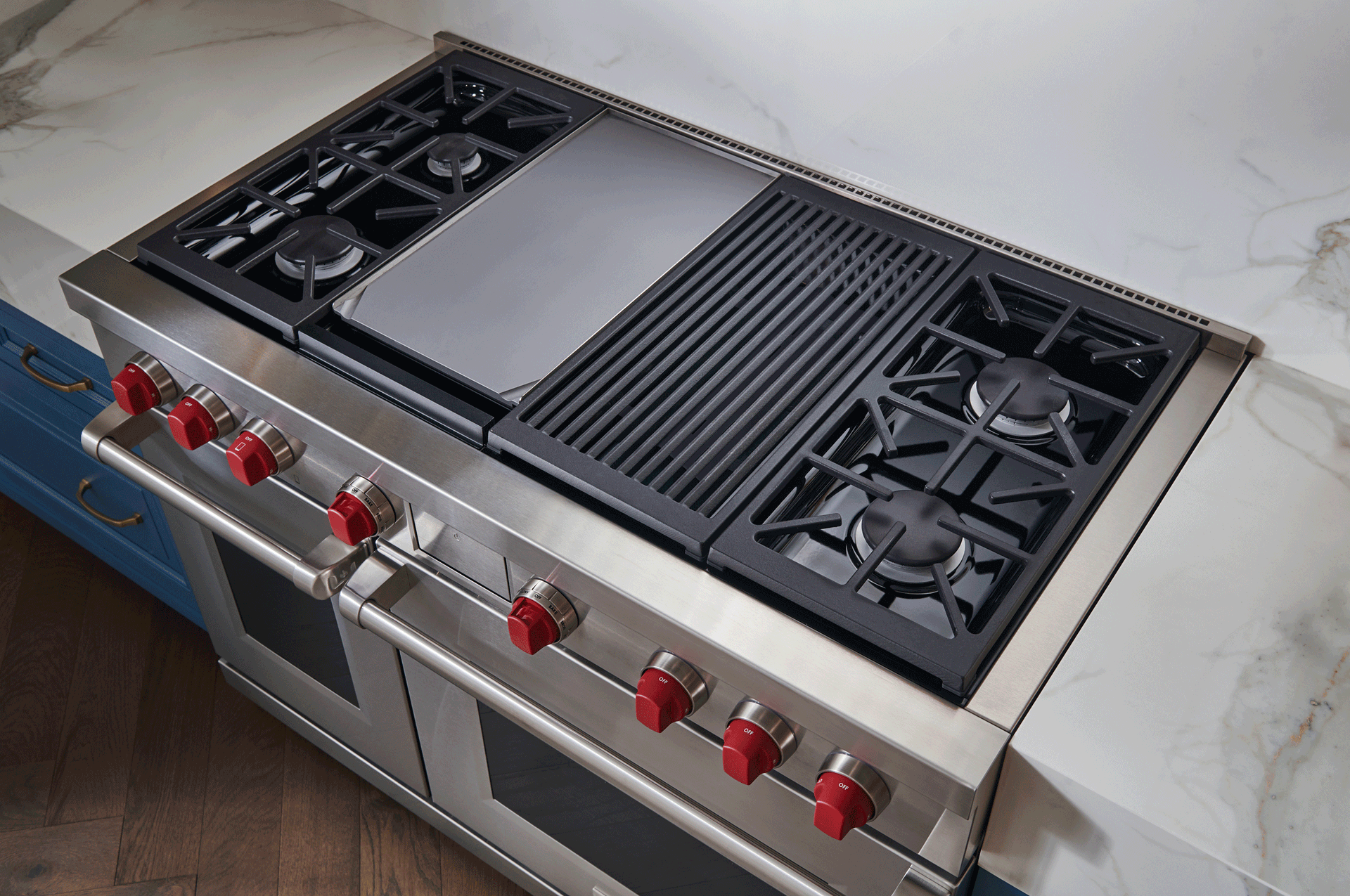 Cuisinière en acier inoxydable avec boutons rouges, plaque de cuisson centrale et deux brûleurs à gaz sur un plan de travail
