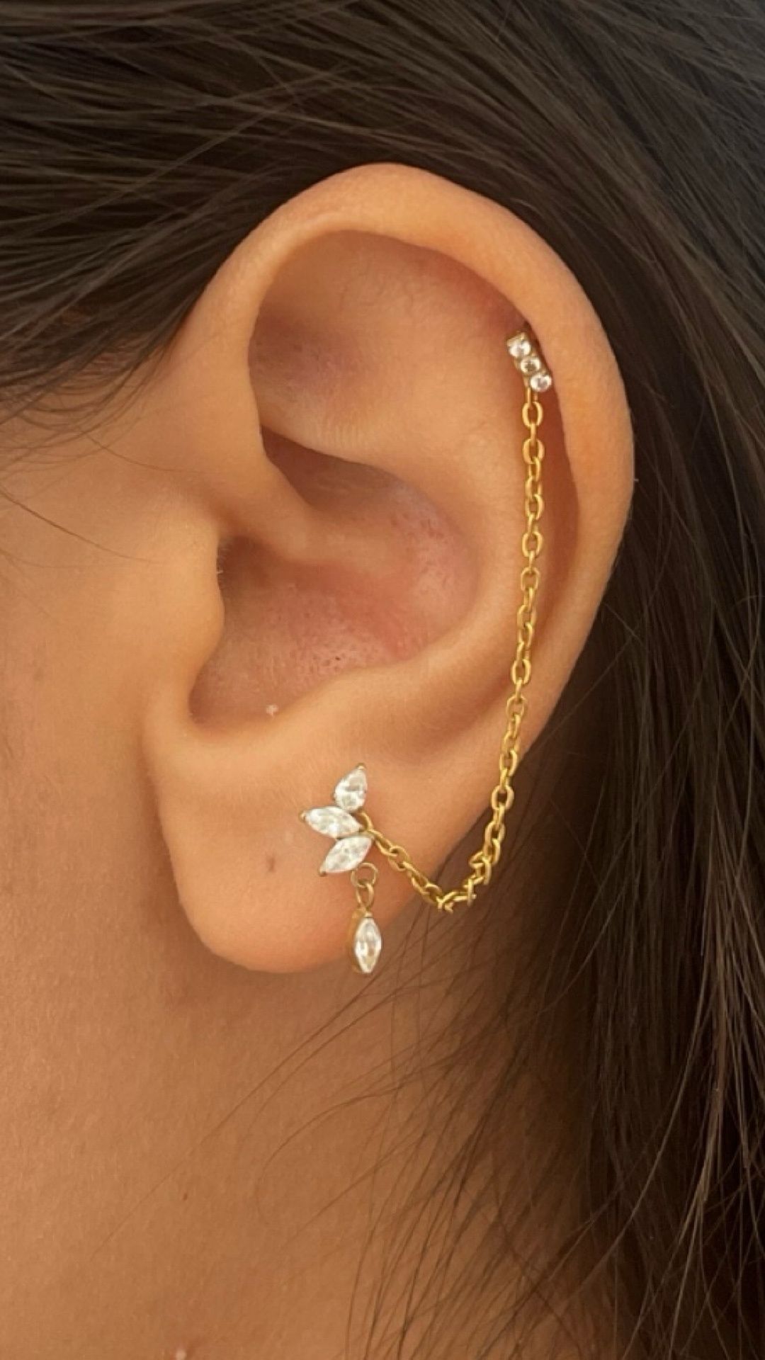 Deux piercings reliés par une chaînette à l'oreille